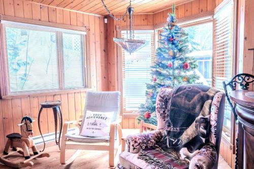 un salon avec un sapin de Noël et une chaise dans l'établissement Sous Bois & Loft - Hot tub - Ski out, à Saint-Faustin–Lac-Carré