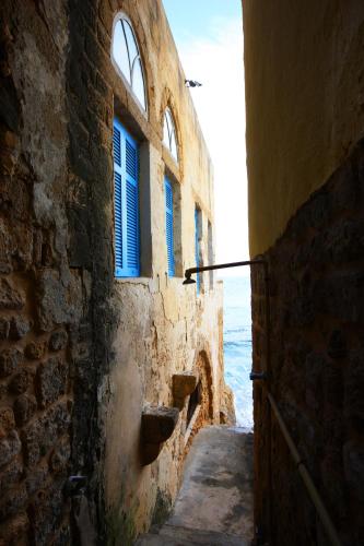 an alley in an old stone building with blue windows at Dar Alma in Soûr