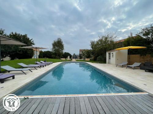 einen Pool mit Stühlen und Sonnenschirmen auf einer Holzterrasse in der Unterkunft Evasion Vendéenne : Charmante Grange avec Spa - FR-1-426-592 in Les Pineaux