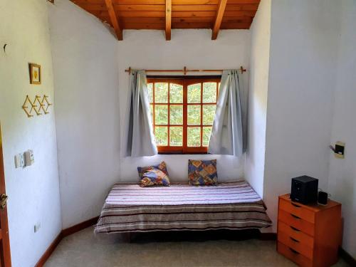 une chambre avec un lit dans une pièce avec une fenêtre dans l'établissement Cabañas Pioneras, à Villa Rumipal
