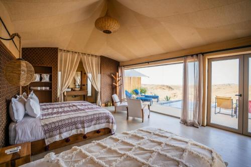 a bedroom with a bed and a view of the desert at SEVEN SAINTS Lodges in El Karia