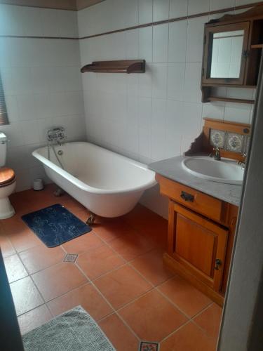 a bathroom with a bath tub and a sink at Pendora Lodge Measroch and Joubert str Piet Retief in Piet Retief