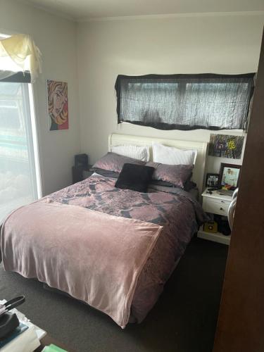 - une chambre avec un grand lit et une couette violette dans l'établissement Ocean Shores Warea, 