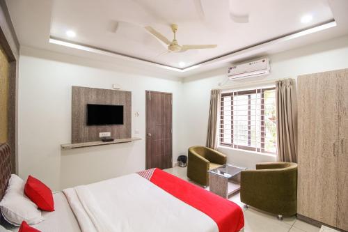 a bedroom with a bed and a tv and chairs at Hotel O Eagle Fantasy in Vānivilāsa Puram