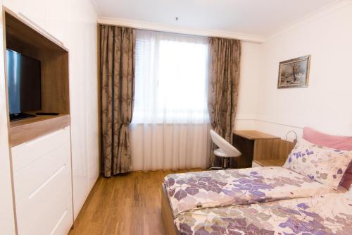 Schlafzimmer mit einem Bett, einem TV und einem Fenster in der Unterkunft Vienna Hauptbahnhof Arsenal Apartments in Wien