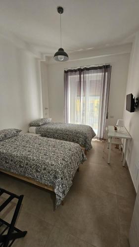 a bedroom with three beds and a table and a window at PETER PAN apartment in Salerno