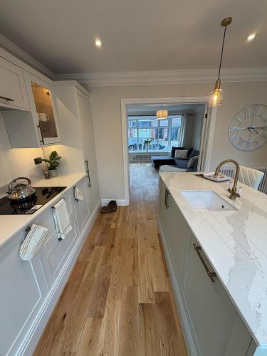 a kitchen with white cabinets and wooden floors at Stylish 3-Bed Home Close to Newcastle City Centre in Kenton