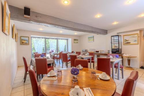 a dining room with wooden tables and chairs at Logis Hôtel Le Manoir Des Portes in Lamballe