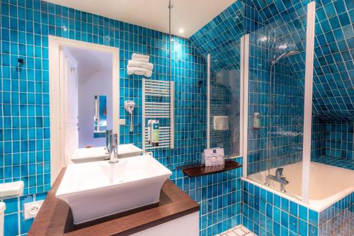 y baño de azulejos azules con lavabo y ducha. en Logis Hôtel Le Manoir Des Portes, en Lamballe