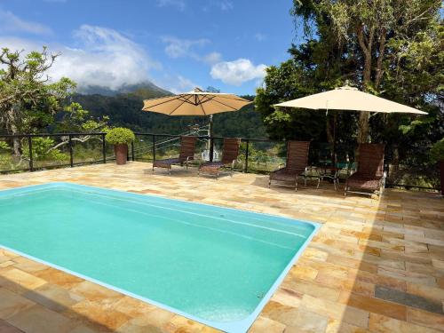 einen Pool mit Stühlen und Sonnenschirmen auf einer Terrasse in der Unterkunft Casa maravilhosa com piscina e sauna in Muri