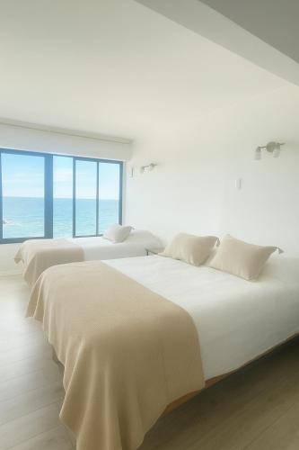 una fila de camas blancas en una habitación blanca en Trimar Hotel, en Concón