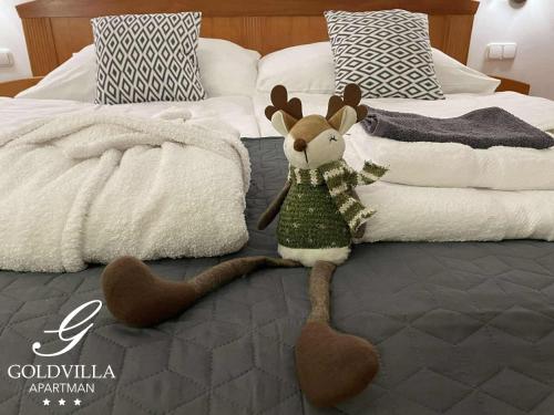 Ein ausgestopftes Rentier sitzt auf einem Bett in der Unterkunft Goldvilla Apartman in Zalakaros