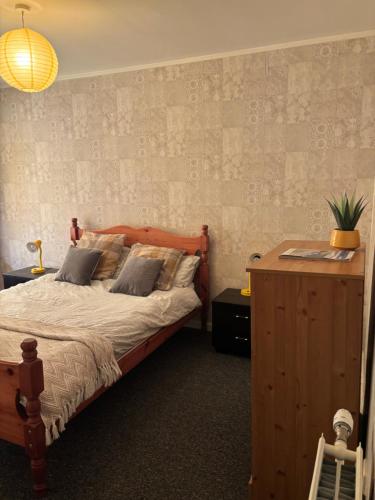a bedroom with a bed with a wooden headboard at OakHouse- Entire 3 Bedroom Terrace House with Free Parking in Cumbernauld