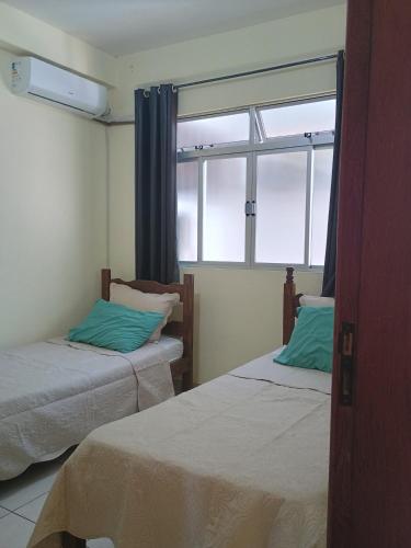 a room with two beds and a window at Ap 2 quartos aconchegante com ar-condicionado in Viçosa