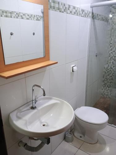 a white bathroom with a sink and a toilet at Ap 2 quartos aconchegante com ar-condicionado in Viçosa