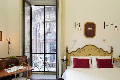 1 dormitorio con cama con almohadas rojas y escritorio en SantuzzaMia, en Catania