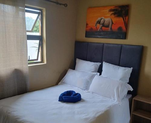a bed with a blue pillow on top of it at Cozy Road Lodge in Sihangwane