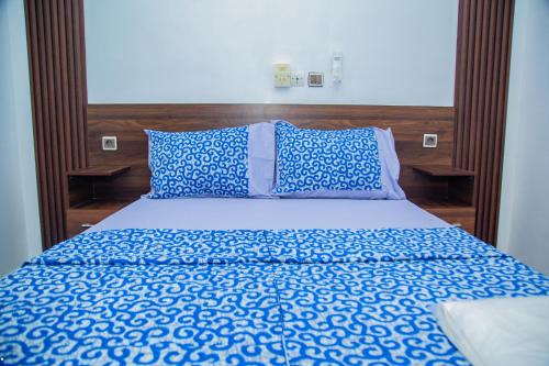 a bed with blue and white sheets and a wooden headboard at Sika Résidence Bénin in Cocotomey