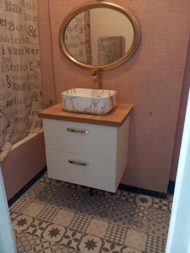 ein Badezimmer mit Waschbecken und Spiegel auf einer Kommode in der Unterkunft Villa Horizon in Champs-Sur-Marne
