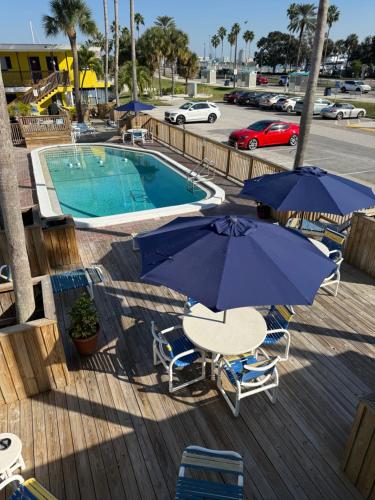 a deck with a pool with chairs and umbrellas at Barefoot Bay Resort Motel in Clearwater Beach