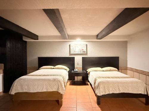 a bedroom with two beds and a table in it at Hotel Mirage Express in Matamoros