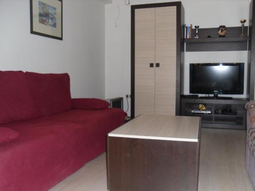 a living room with a red couch and a tv at Pansion Alfa in Međugorje