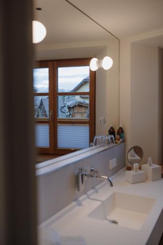 a bathroom with a large mirror and a sink at Mesnerhaus & Gourmetrestaurant Mesnerhaus mit 4 Hauben in Mauterndorf