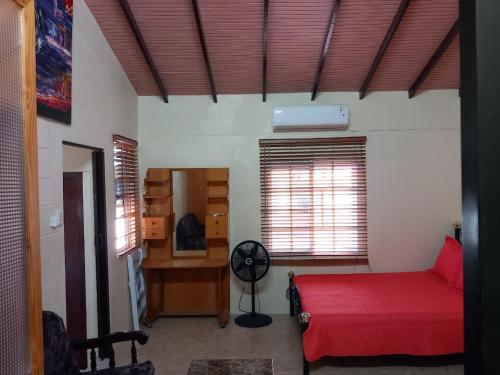 a bedroom with a red bed and a desk and windows at Diamond Breeze - Fully furnished apartment in Port-of-Spain