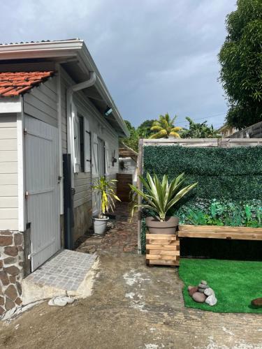 a house with a shed and a yard with plants at Résidence Flores De Maria in Le Marin