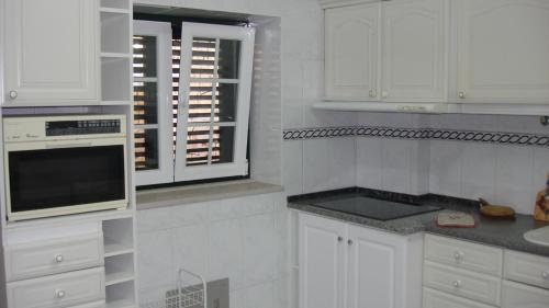 cocina blanca con armarios blancos y ventana en Casa de Férias Azeitão, en Azeitão