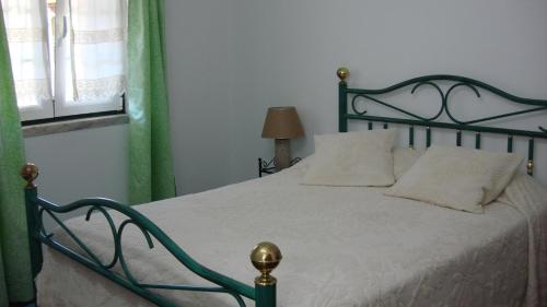 a bedroom with a bed with a green frame and a window at Casa de Férias Azeitão in Azeitao