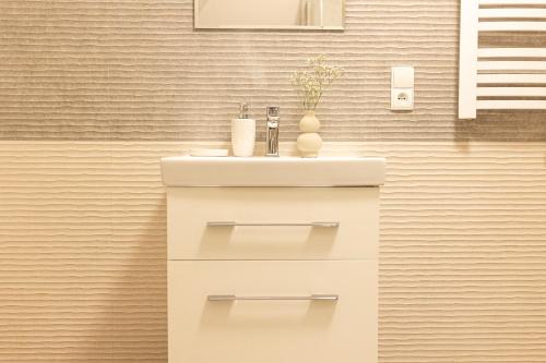 La salle de bains est pourvue d'un lavabo blanc et d'un comptoir. dans l'établissement Spokojny Apartament u Słodyczki w Kluszkowcach, à Kluszkowce