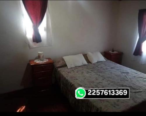 a bedroom with a bed with two night stands and two windows at Es Lo Que Hay in Nueva Atlantis