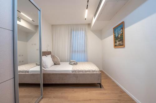 une petite chambre avec un lit et un miroir dans l'établissement מיקונוס על הים נהריה, à Nahariya