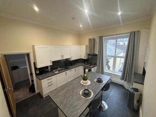 a kitchen with white cabinets and a large window at Bay Apartment in Morecambe