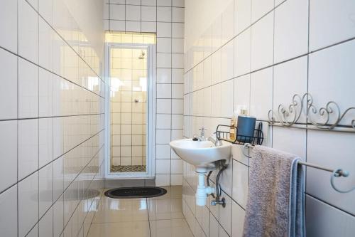 ein weißes Badezimmer mit Waschbecken und Spiegel in der Unterkunft Casa Bliss, Stylish City Escape in Windhoek