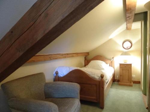 une chambre mansardée avec un lit et une chaise dans l'établissement Auberge Des Chasseurs, à Échenevex