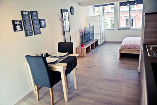 a dining room with a table and chairs and a room at Appart-Hotel Léopold Liège Centre in Liège