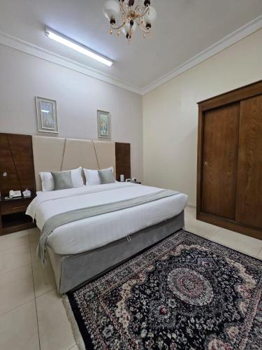 a bedroom with a large bed and a rug at مسكن راحتك للشقق المخدومه in Tabuk
