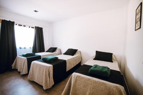 een kamer met drie bedden met groene kussens erop bij Complejo Malama Kai in Mar de Cobo
