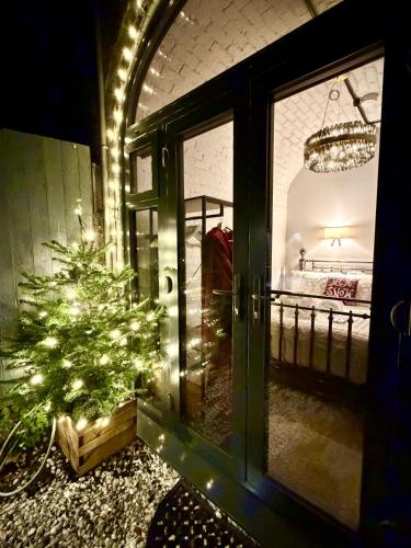 a christmas tree in front of a door with lights at Ironbridge Tiny Hideaway in Ironbridge