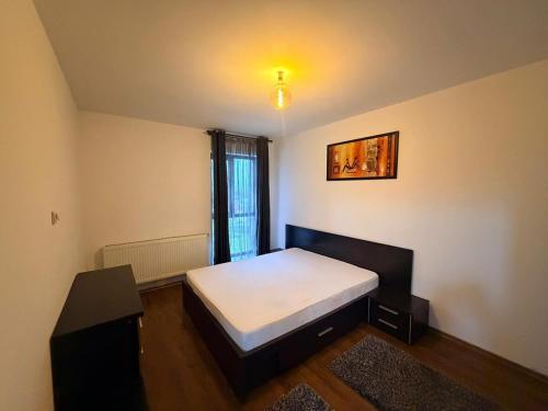 a small bedroom with a bed and a window at Modern apartment in Ford-Ferval area, Craiova in Craiova
