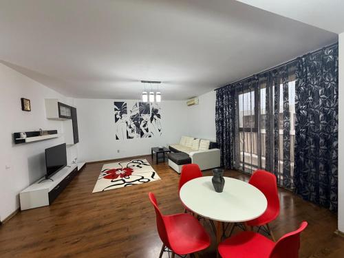 a living room with a table and red chairs at Modern apartment in Ford-Ferval area, Craiova in Craiova
