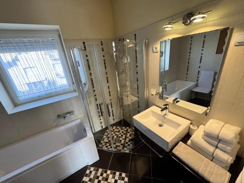 een badkamer met een wastafel, een bad en een spiegel bij LUX Apartman in Balatonfüred