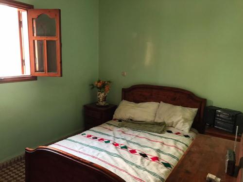 a green bedroom with a bed with a wooden headboard at LoveWave House in Agadir