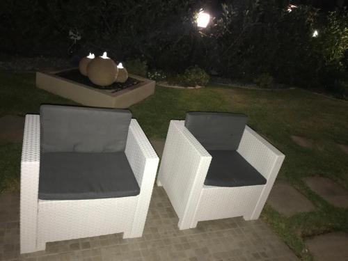 Dos sillas de mimbre sentadas junto a una fuente por la noche. en Pine Beach House, en Campofelice di Roccella