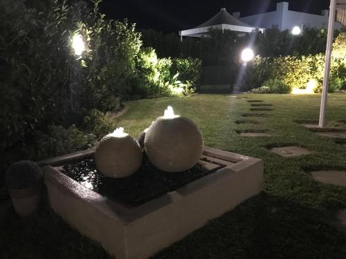 Dos jarrones blancos colocados encima de una fuente por la noche. en Pine Beach House, en Campofelice di Roccella