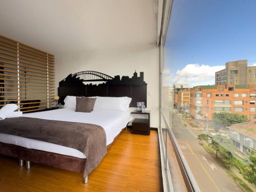 a bedroom with a large bed and a large window at Hotel Regency Suites La Feria in Bogotá