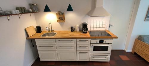 a small kitchen with a sink and a stove at Købmandsgården i Grundfør in Hinnerup