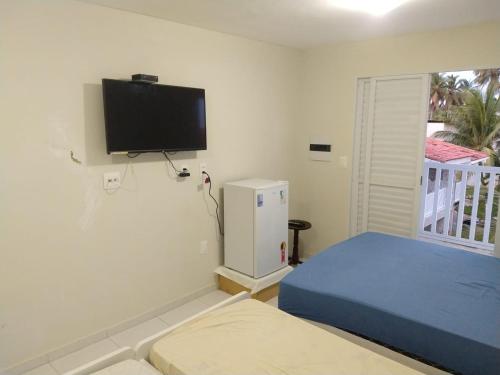 ein Schlafzimmer mit einem Bett und einem Fernseher an der Wand in der Unterkunft Village Galés Maragogi in Maragogi